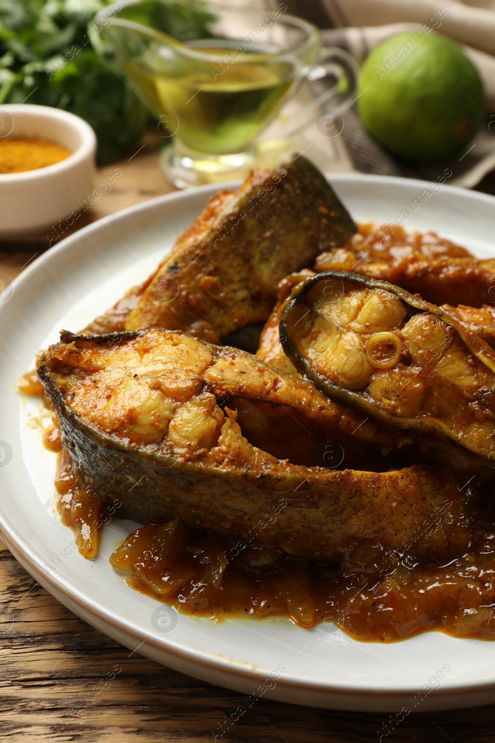 Photo of Tasty Indian fish curry on wooden table, closeup