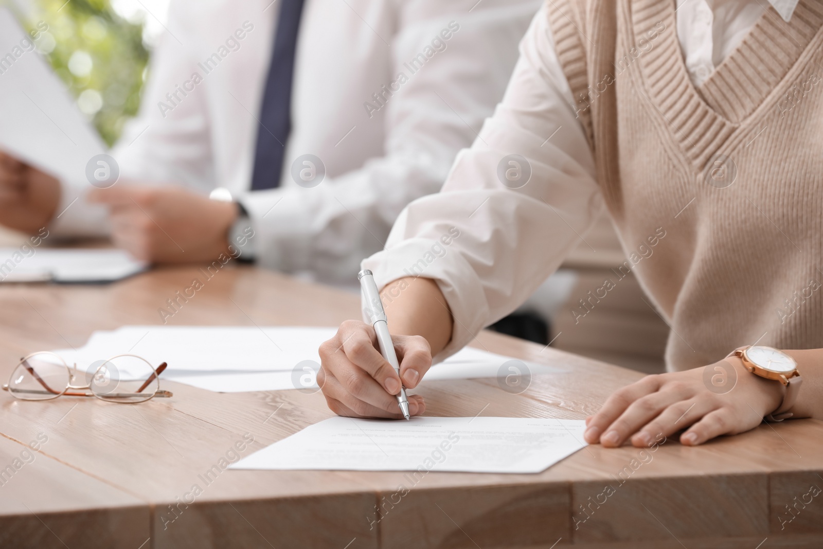 Photo of Woman signing contract at table in office, closeup.