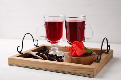 Photo of Beautiful Hibiscus flower and delicious tea on white wooden table