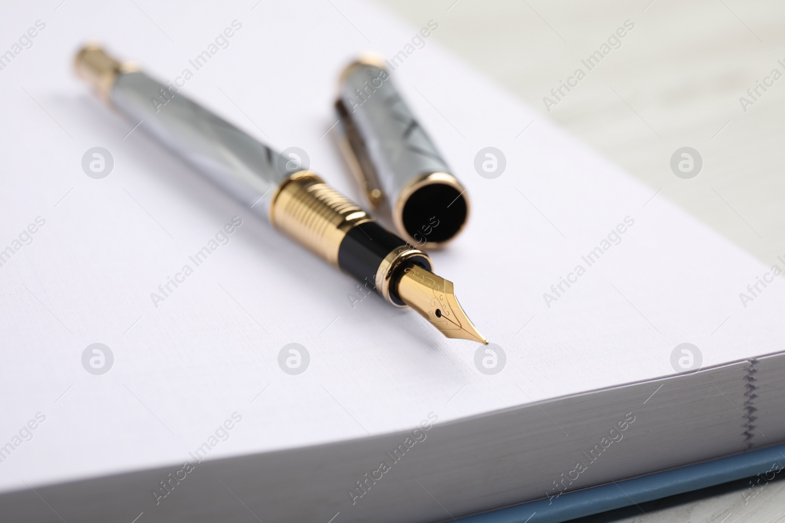 Photo of Stylish fountain pen on open notebook, closeup