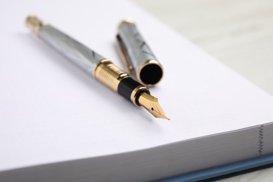 Stylish fountain pen on open notebook, closeup