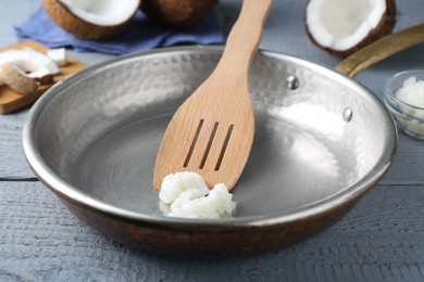 Photo of Frying pan with coconut cooking oil and spatula on grey wooden table, closeup
