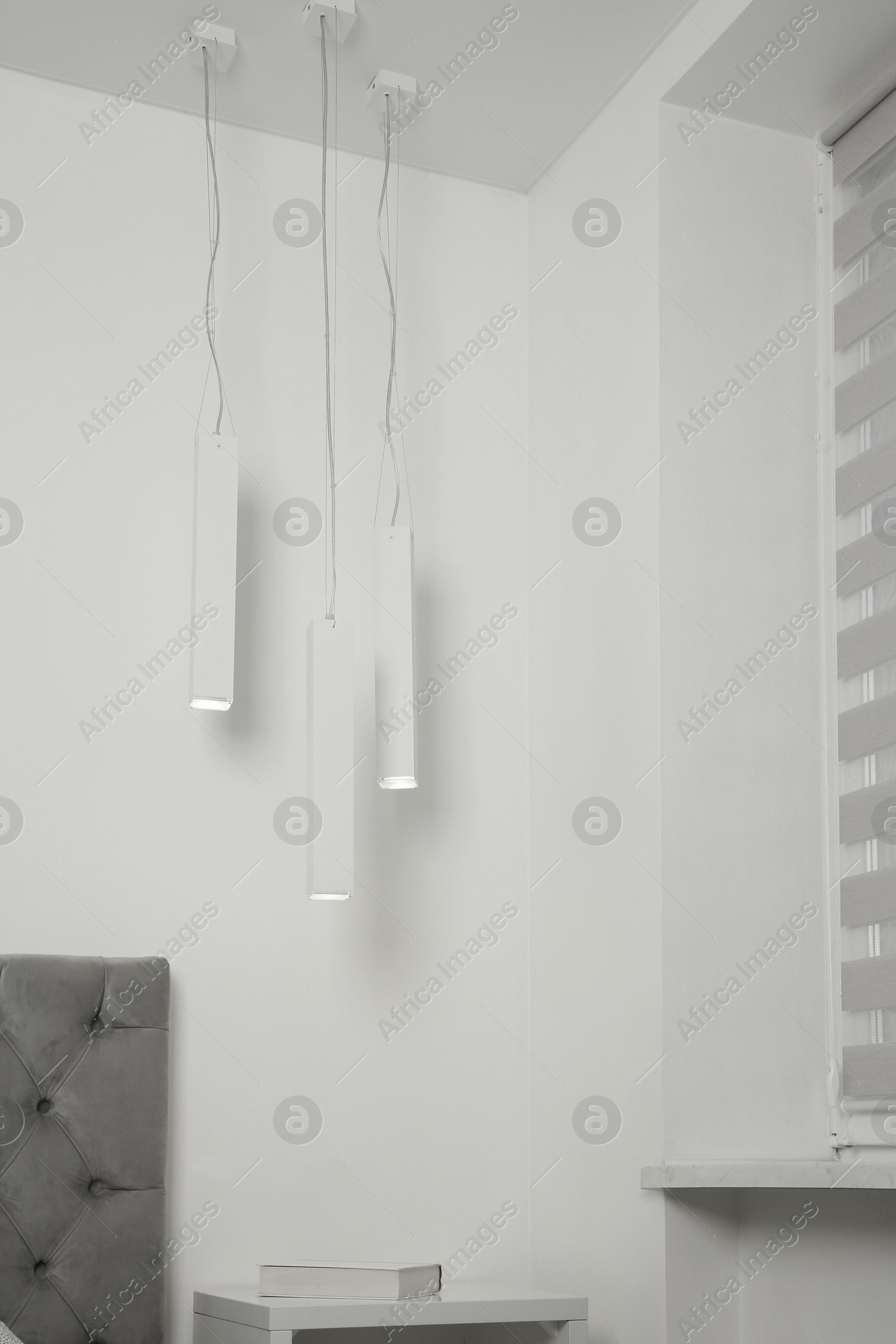 Photo of Stylish pendant lamps hanging over nightstand in light room
