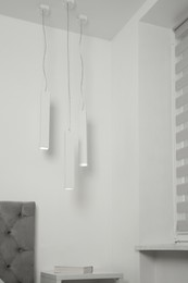 Photo of Stylish pendant lamps hanging over nightstand in light room