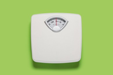 Bathroom scale on light green background, top view