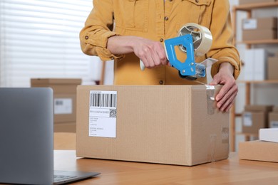 Photo of Seller taping parcel at workplace, closeup. Online store