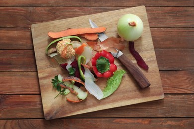 Photo of Peels, knife and fresh vegetables on wooden table, top view