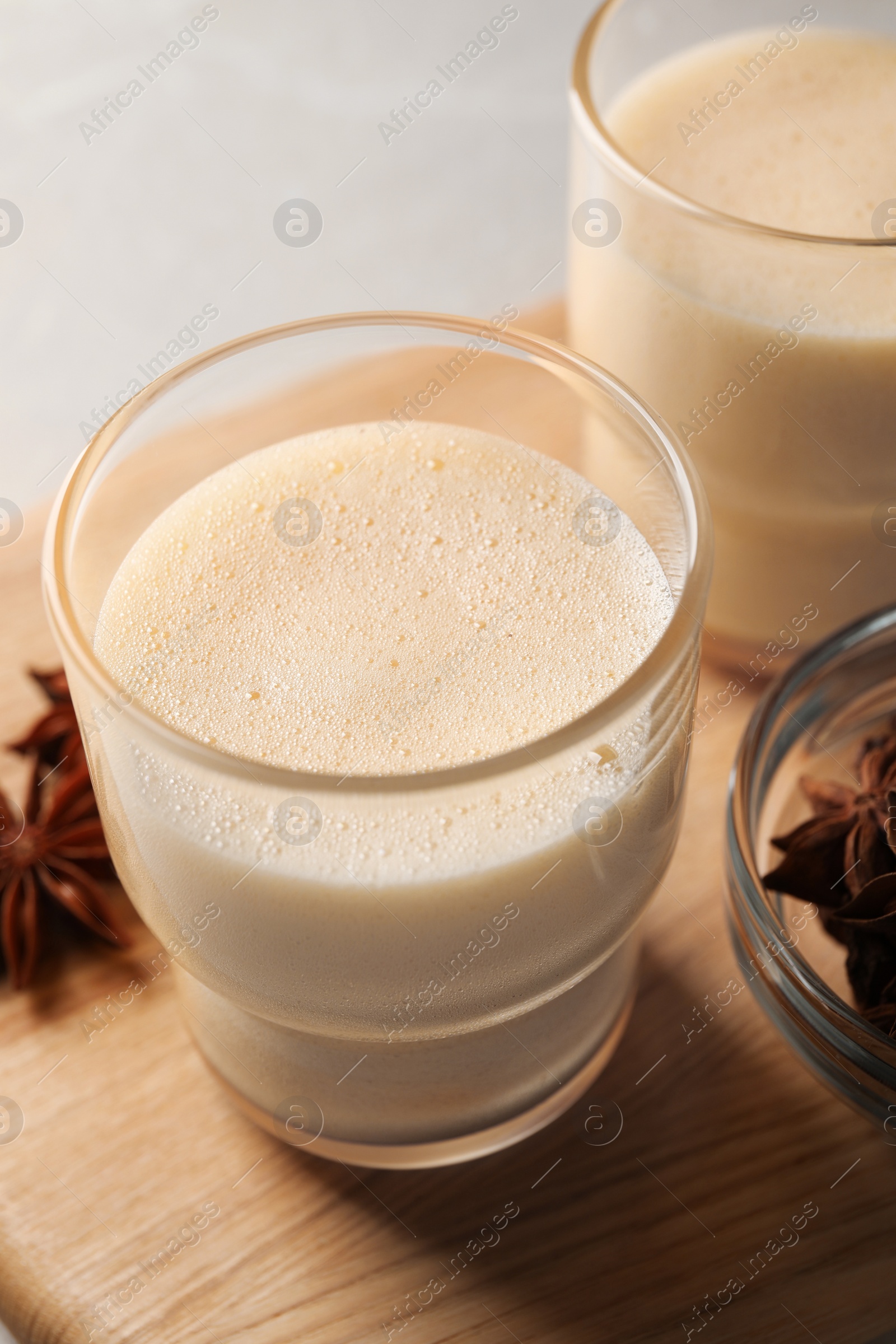 Photo of Glasses of delicious eggnog with anise on grey marble table, closeup