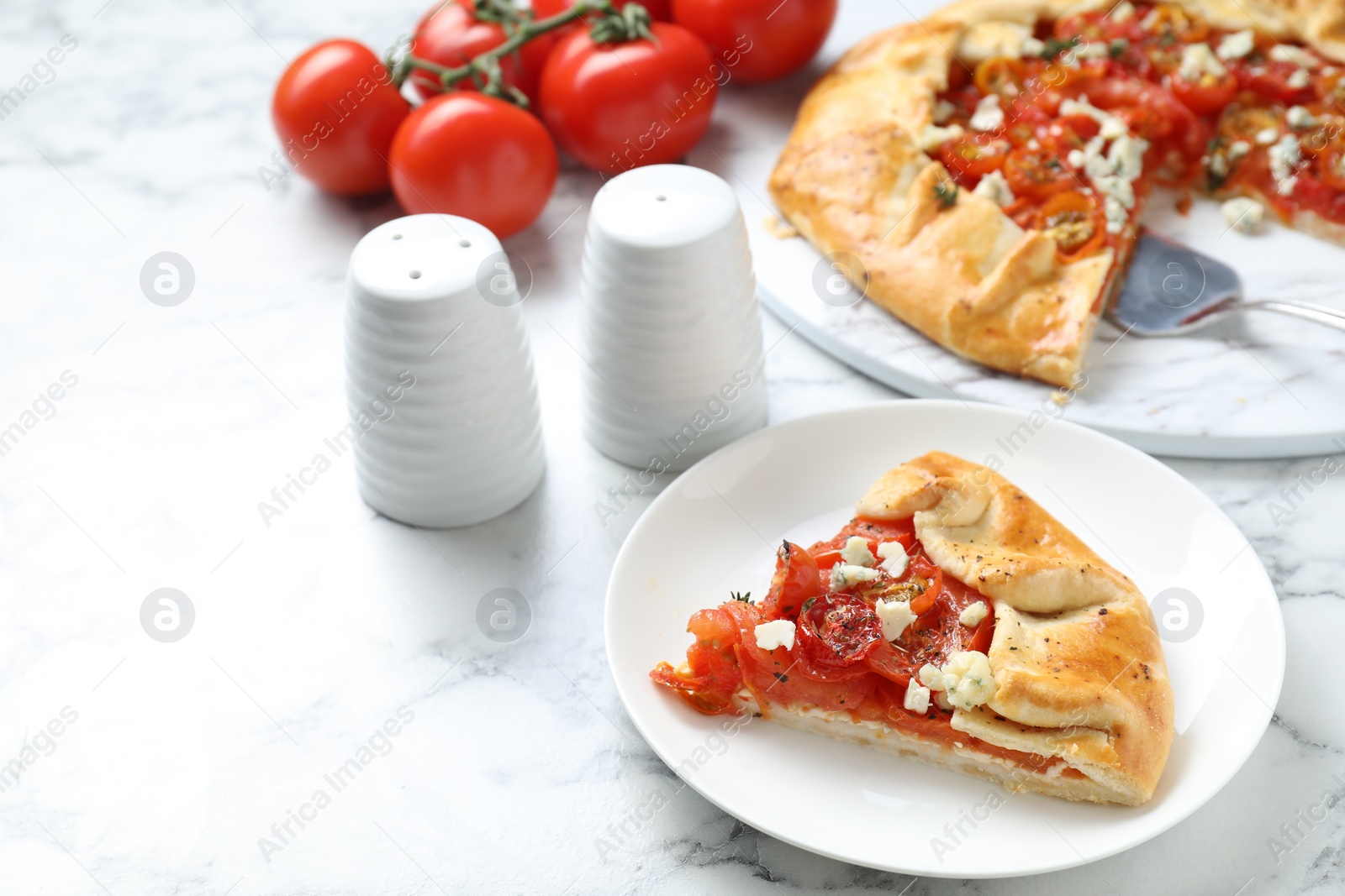 Photo of Tasty galette with tomato and cheese (Caprese galette) on white marble table, closeup. Space for text