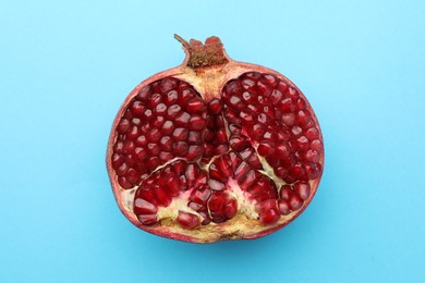 Photo of Cut fresh pomegranate on light blue background, top view