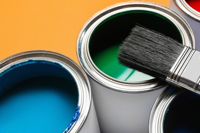 Closeup view of paint cans and brush on color background