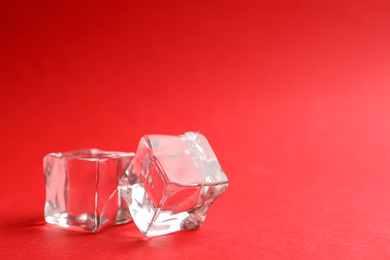 Photo of Crystal clear ice cubes on red background. Space for text