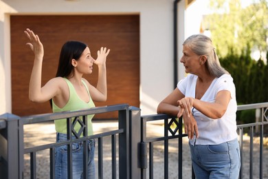 Photo of Emotional neighbours having argument near fence outdoors