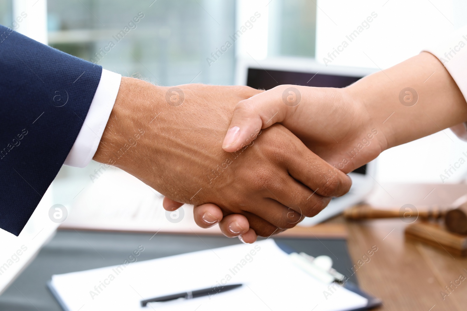 Photo of Male lawyer shaking hands with woman over table, closeup