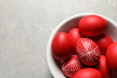 Photo of Bowl with red painted Easter eggs on table, above view. Space for text