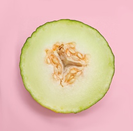 Photo of Half of ripe tasty melon on pink background, top view