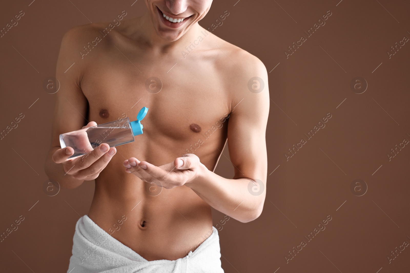 Photo of Man with body lotion on brown background, closeup. Space for text