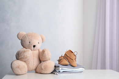 Photo of Child's clothes and toy bear on white table indoors, space for text