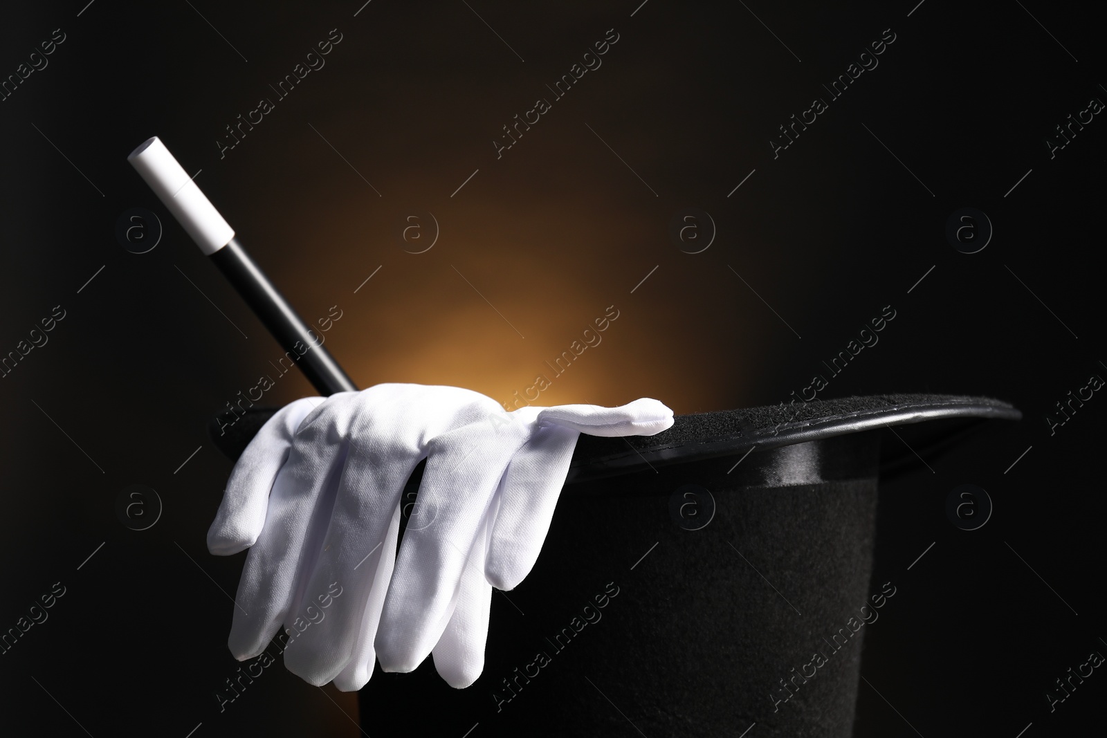 Photo of Magician's hat, gloves and wand on dark background, closeup