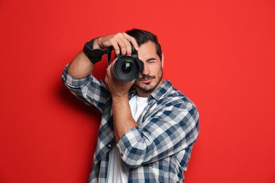 Photo of Young professional photographer taking picture on red background