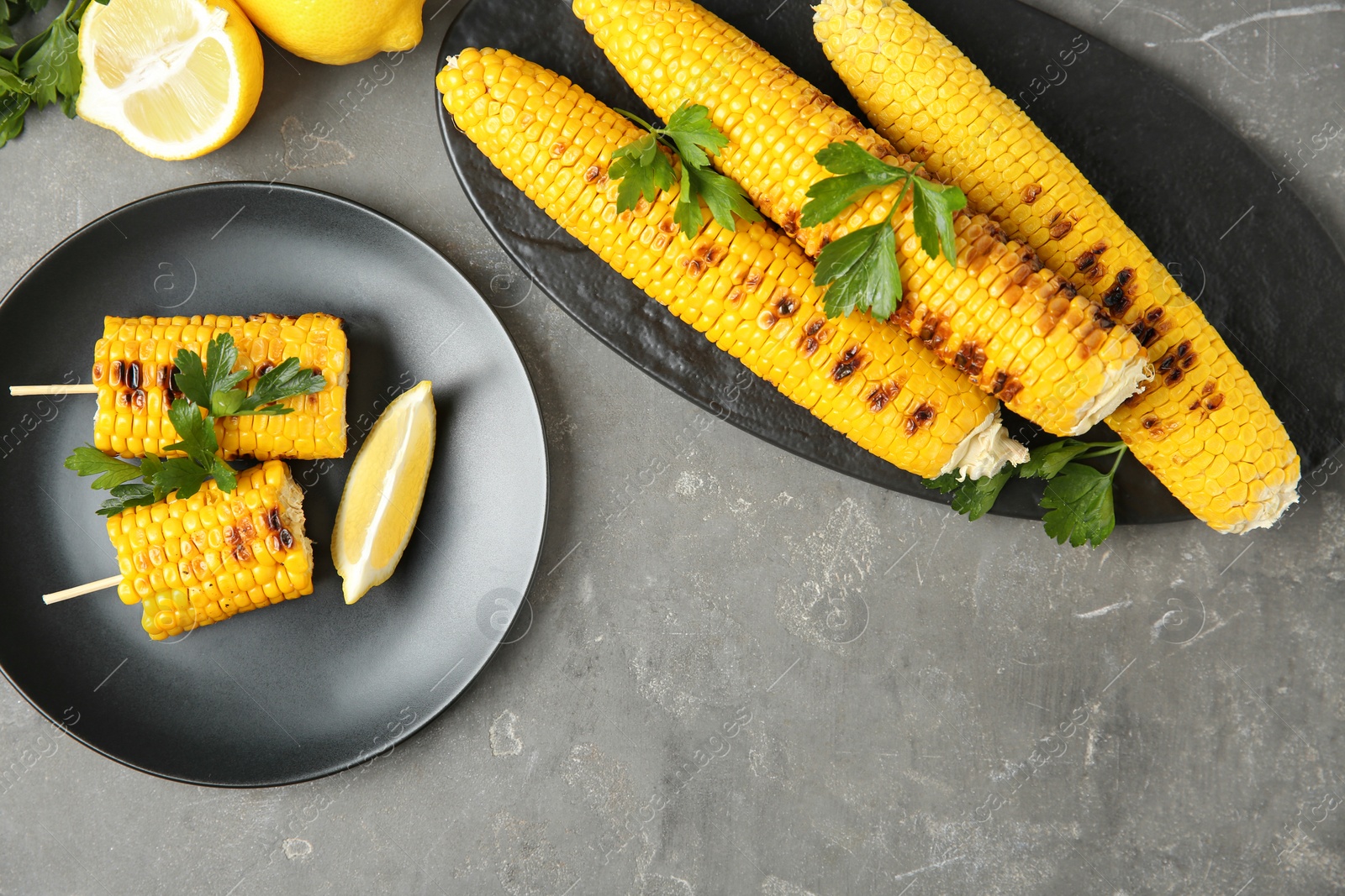 Photo of Flat lay composition of grilled corn cobs on grey table