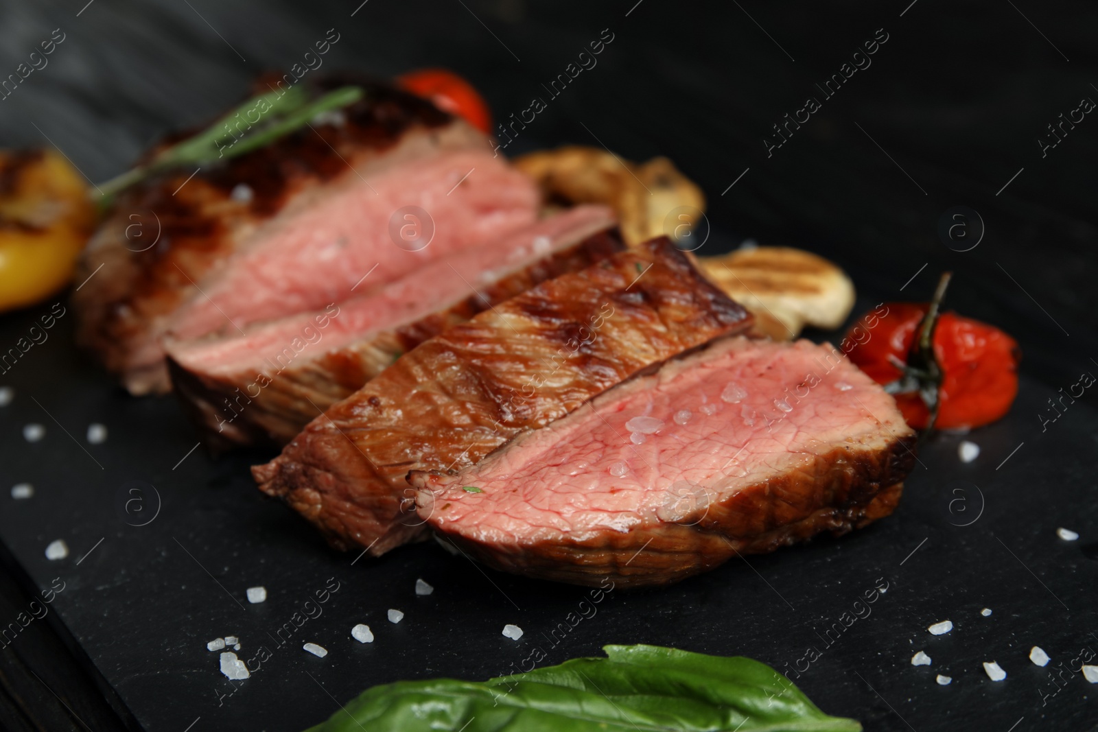 Photo of Grilled meat served with garnish on slate plate, closeup