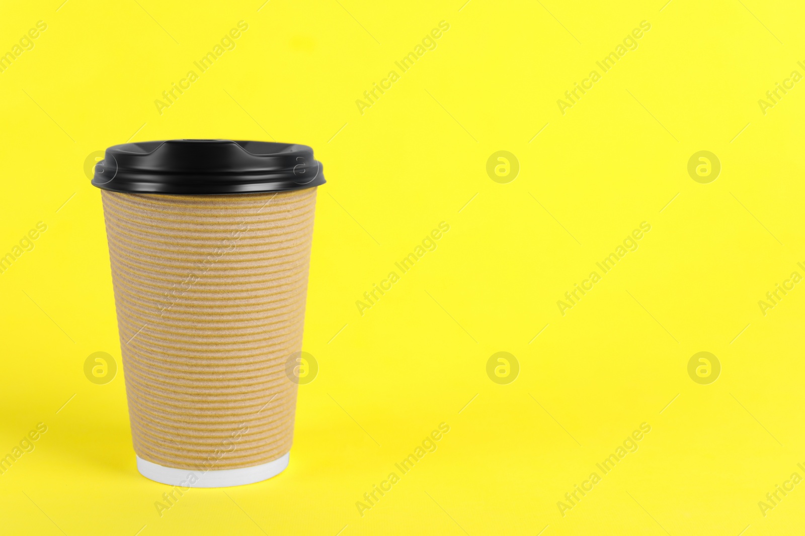 Photo of Paper cup with plastic lid on yellow background, space for text. Coffee to go