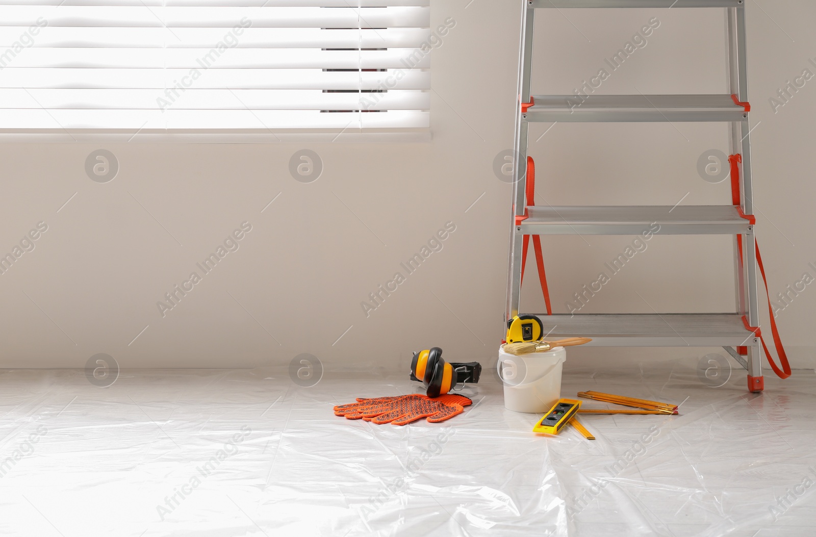 Photo of Stepladder and different tools near wall in room, space for text. Interior renovation