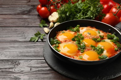 Photo of Delicious shakshuka in frying pan on wooden table. Space for text