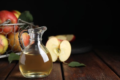 Photo of Natural apple vinegar and fresh fruits on wooden table. Space for text