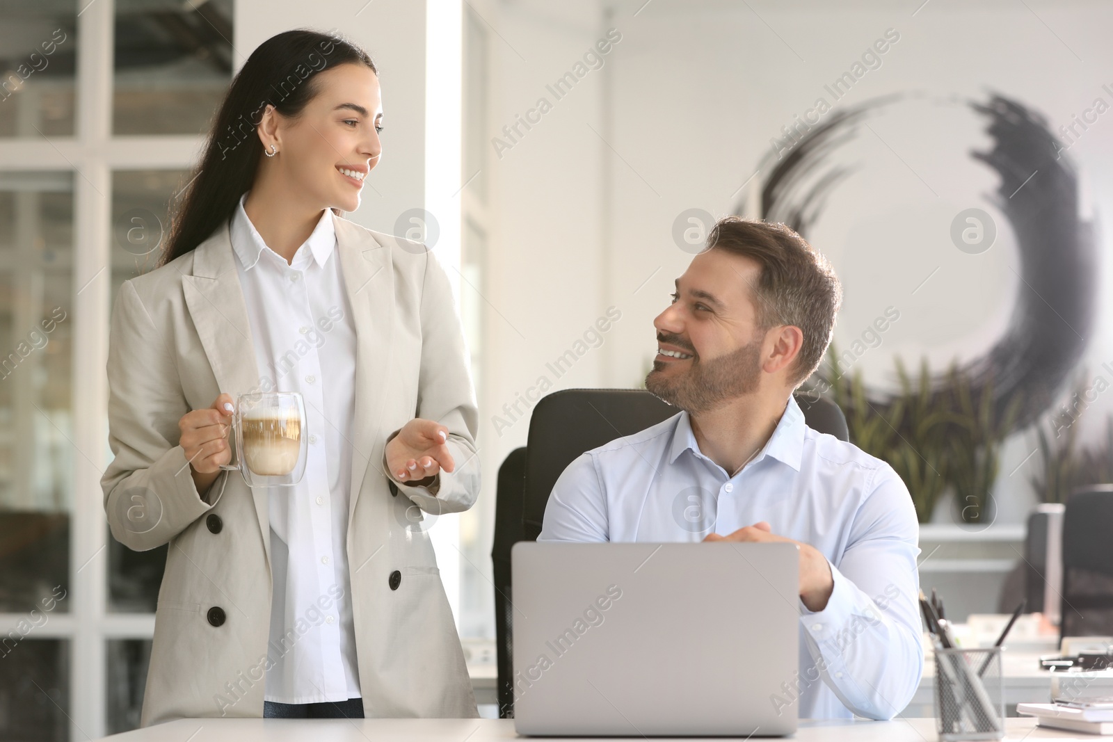 Photo of Colleagues working on laptop at desk in office