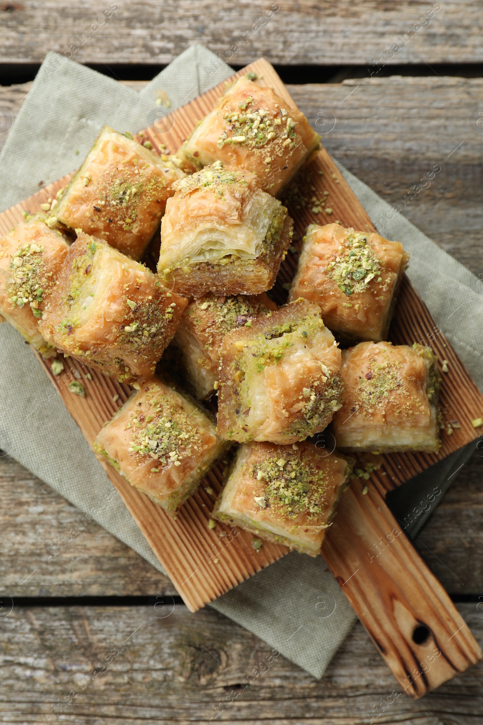 Photo of Delicious fresh baklava with chopped nuts on wooden table, top view. Eastern sweets