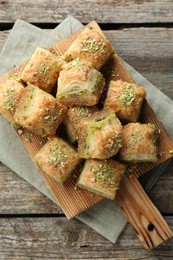 Photo of Delicious fresh baklava with chopped nuts on wooden table, top view. Eastern sweets