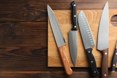 Photo of Many different knives and board on wooden table, top view. Space for text