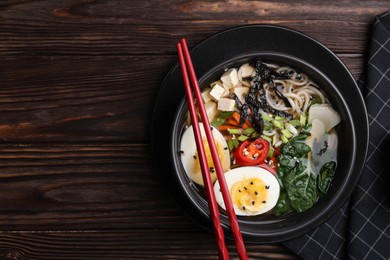 Delicious vegetarian ramen served on wooden table, top view with space for text. Noodle soup