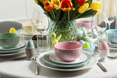 Photo of Easter celebration. Festive table setting with beautiful flowers and painted eggs