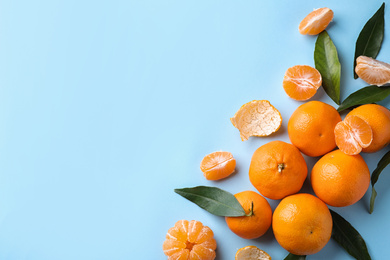 Fresh ripe tangerines on light blue background, flat lay. Space for text