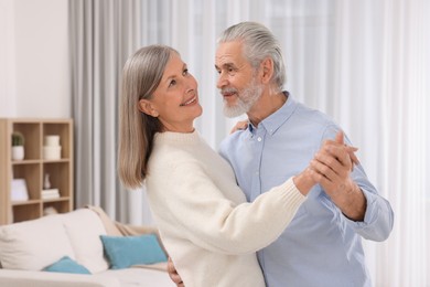 Happy affectionate senior couple dancing at home