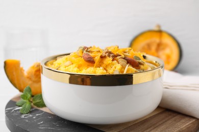 Photo of Tasty cornmeal with nuts, pumpkin and seeds in bowl on table, closeup