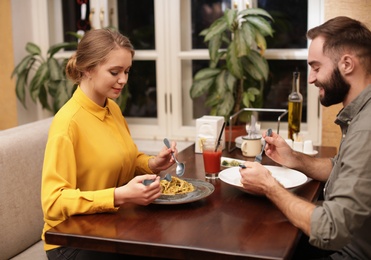 Photo of Lovely young couple having pasta carbonara for dinner at restaurant