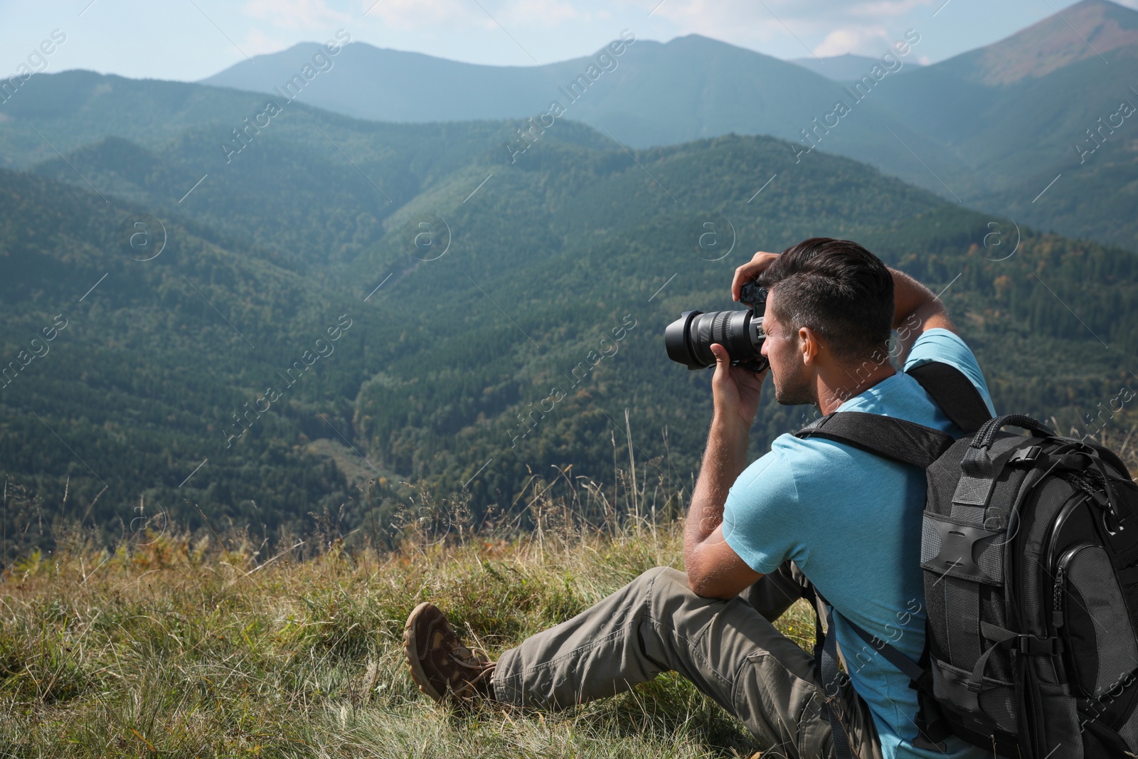 Photo of Professional photographer taking picture with modern camera in mountains. Space for text