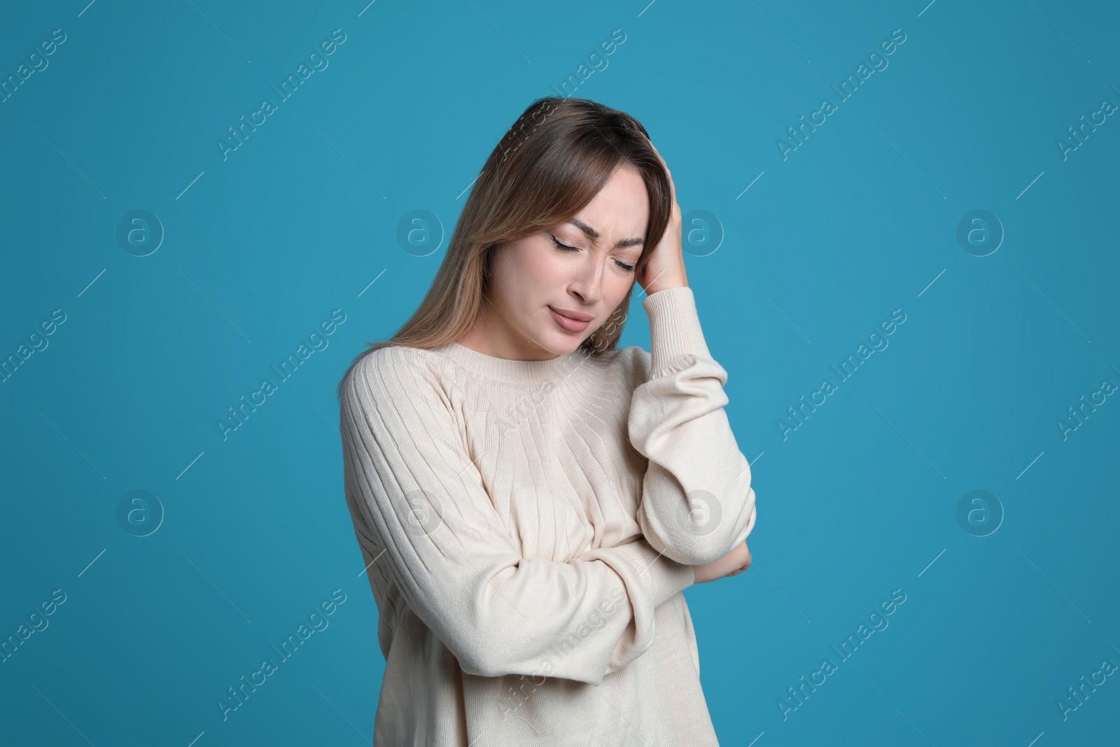 Photo of Young woman suffering from headache on light blue background