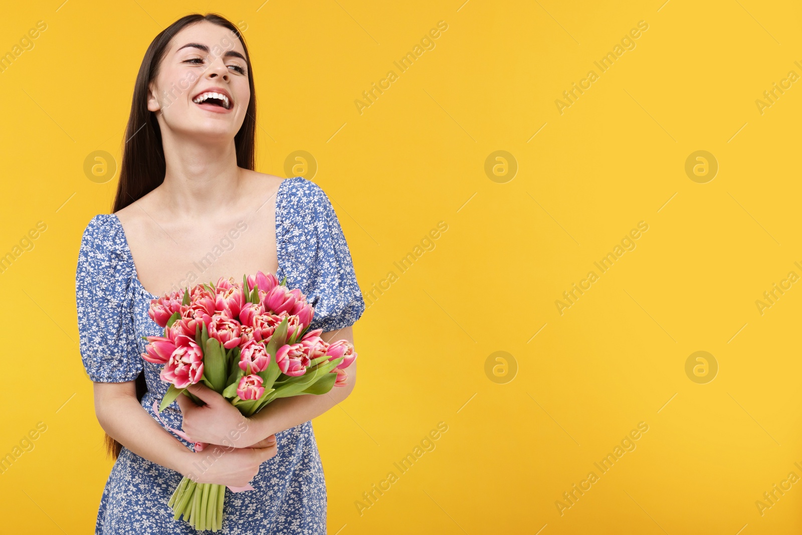 Photo of Happy young woman with beautiful bouquet on orange background. Space for text