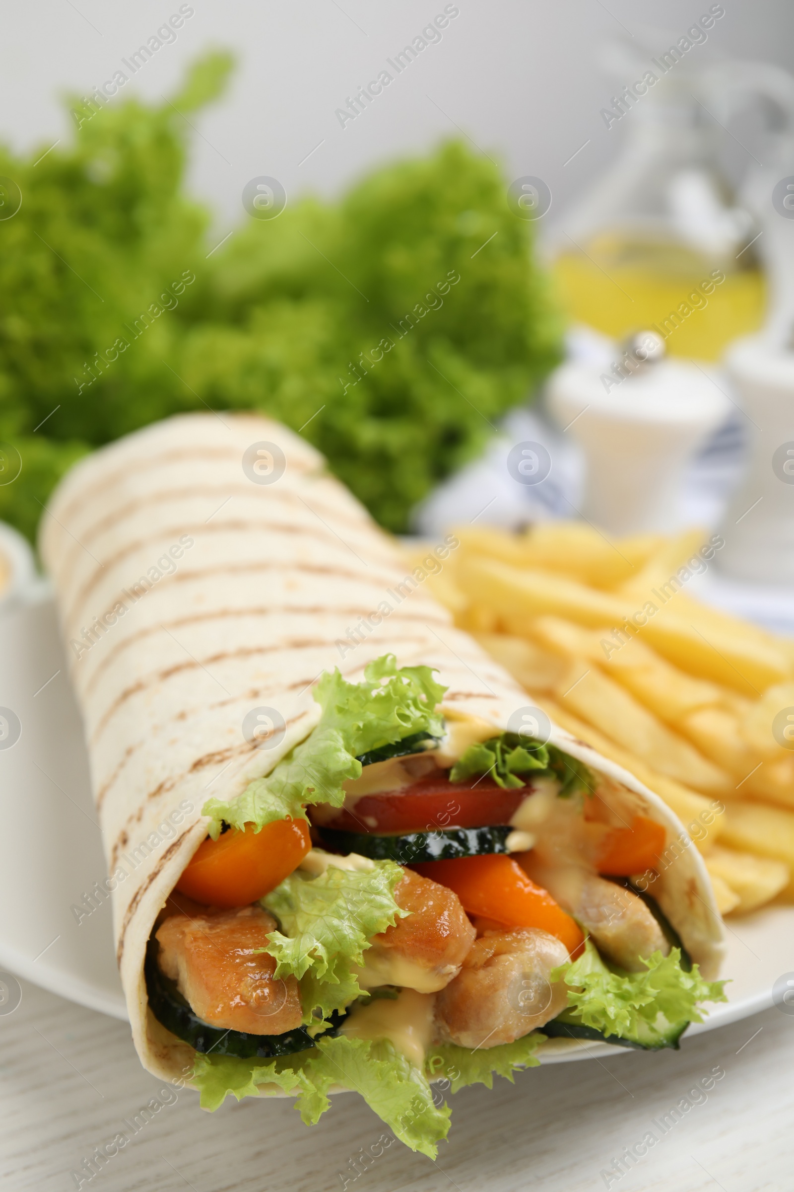 Photo of Delicious shawarma with chicken meat and fresh vegetables served on white wooden table, closeup