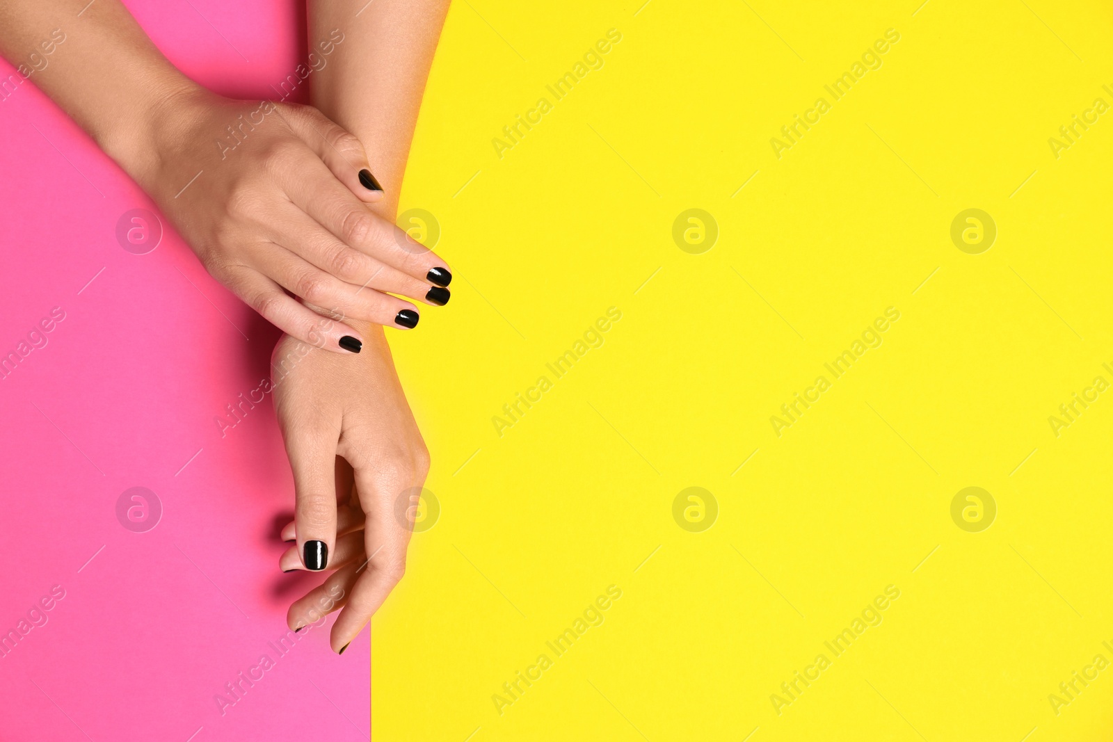 Photo of Woman showing black manicure on color background, top view with space for text. Nail polish trends