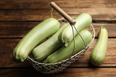 Photo of Basket with ripe zucchinis on wooden table