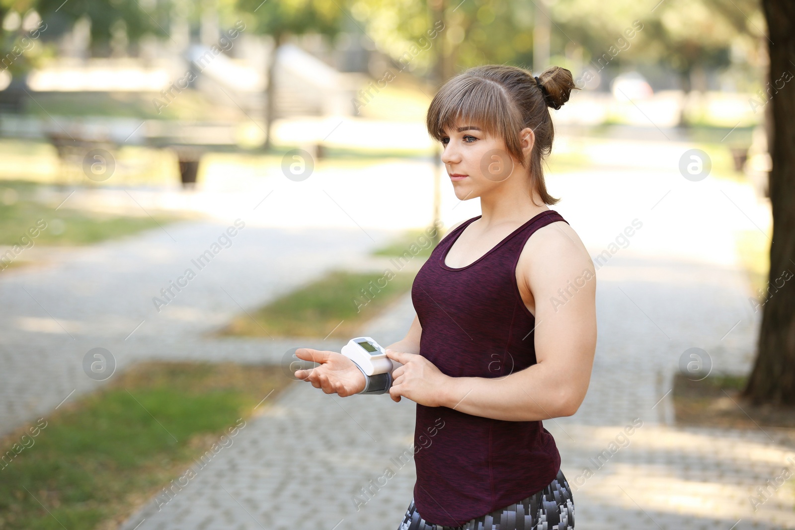 Photo of Young woman checking pulse after workout in park