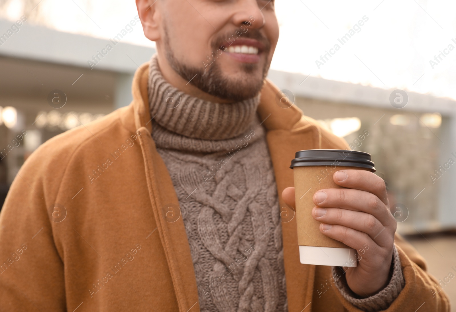 Photo of Man with cup of coffee on city street in morning, closeup