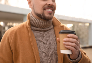 Photo of Man with cup of coffee on city street in morning, closeup