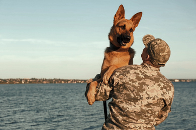 Man in military uniform with German shepherd dog outdoors